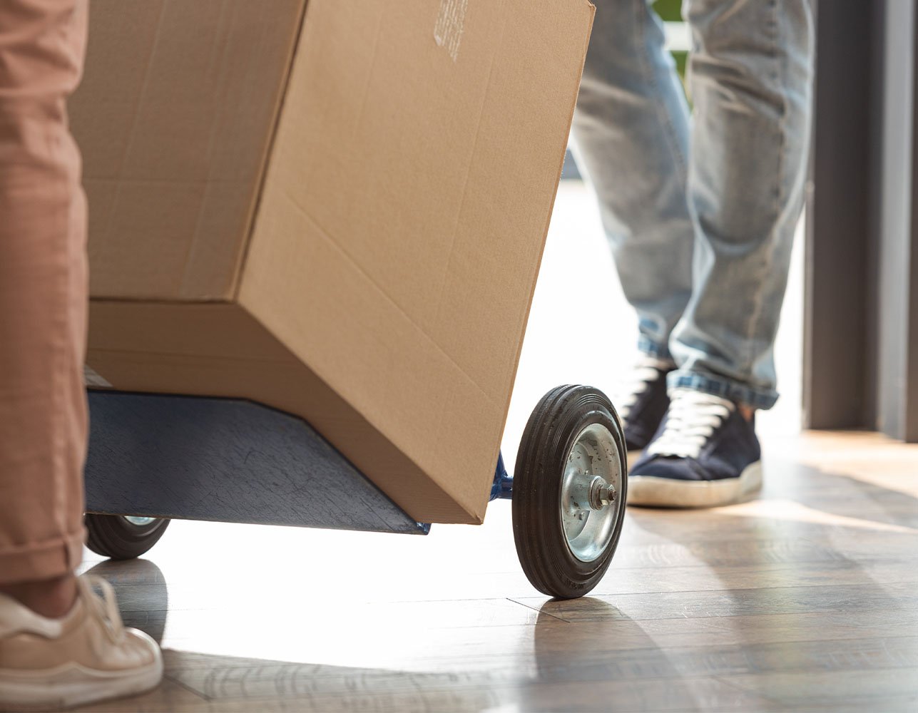 Cropped view of a delivery man pushing a hand cart with a wrapped box