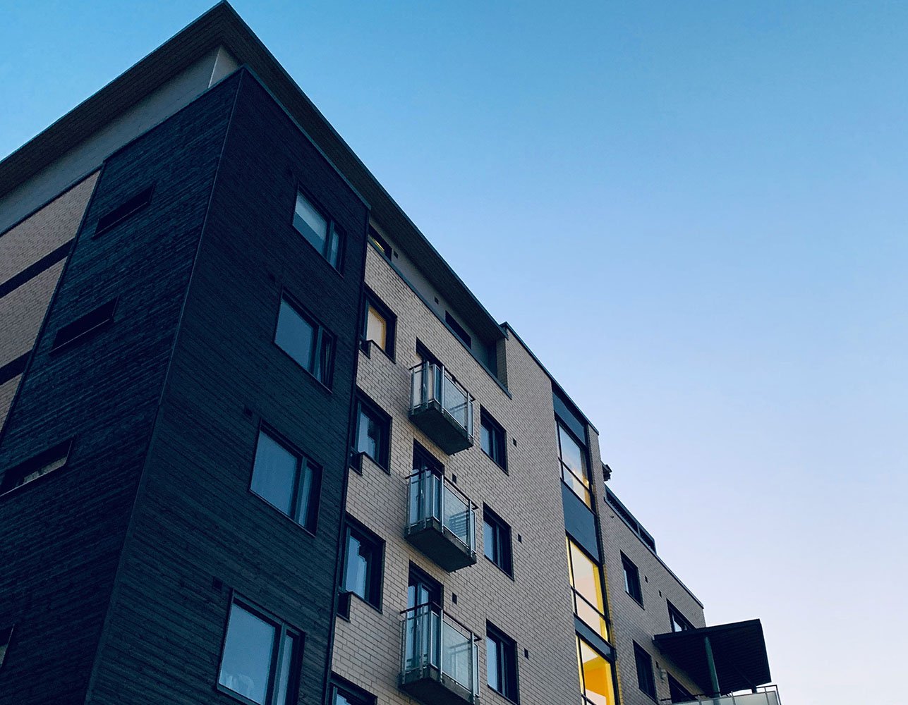Low-angle view of a modern multi-story apartment building at dusk