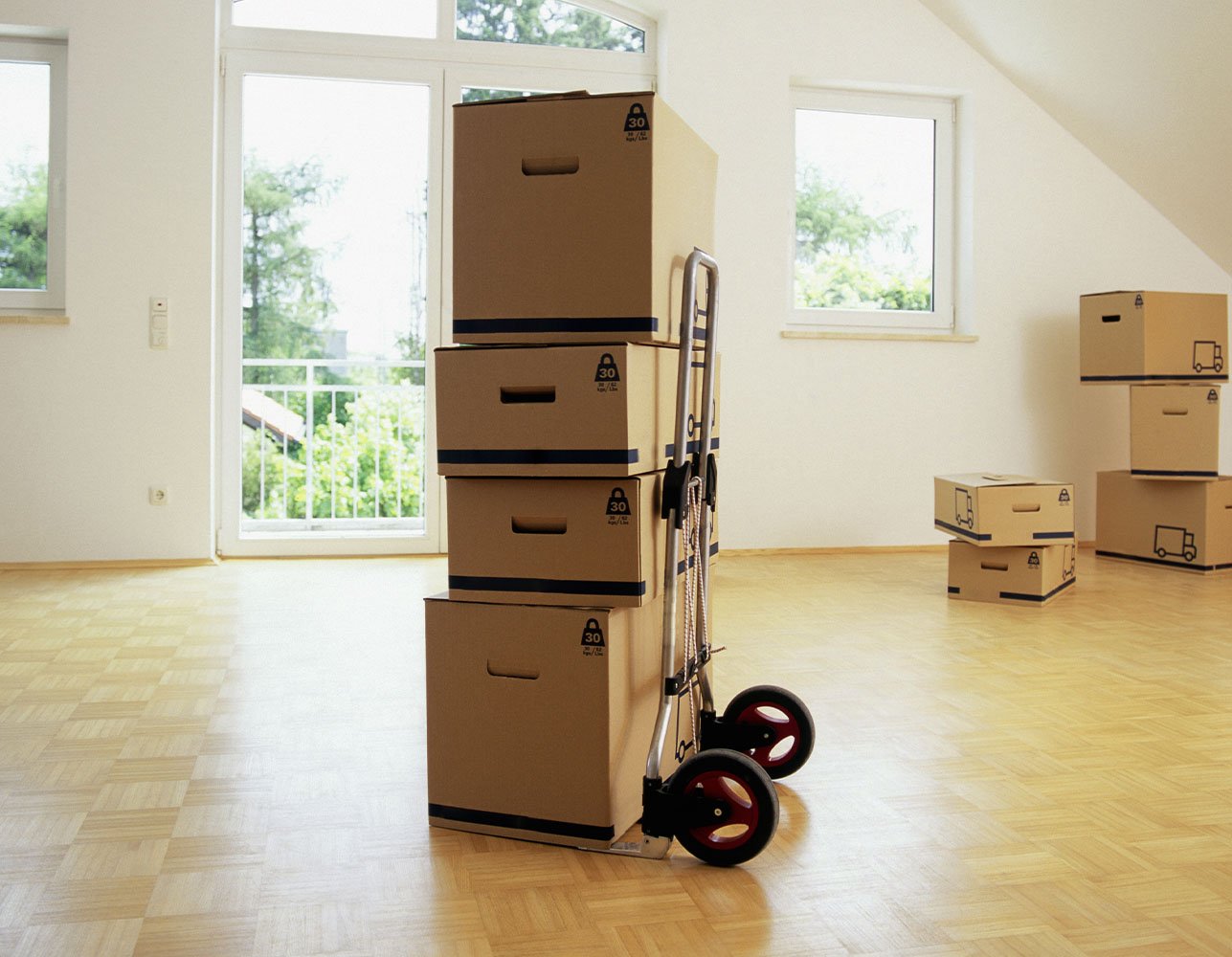 Cardboard moving boxes stacked in a bright room near a window