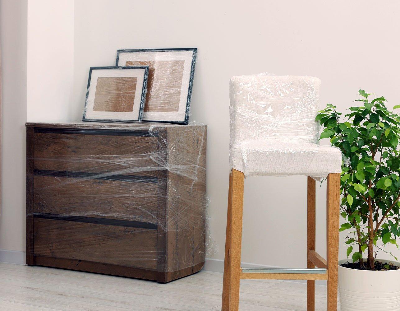 Wooden dresser and stool with a green plant in a softly lit bedroom
